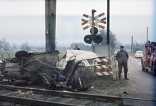 117436 Afbeelding van een verongelukte auto op een met AKI's beveiligde spoorwegovergang in de Nieuwe Weteringseweg ...